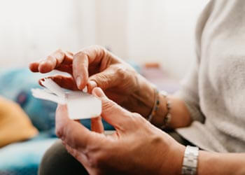 picking a pill out of a container